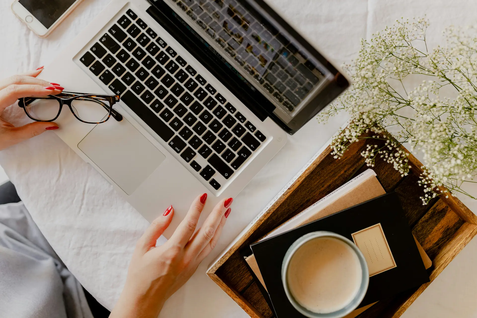 Hands on a laptop next to a cup of coffee